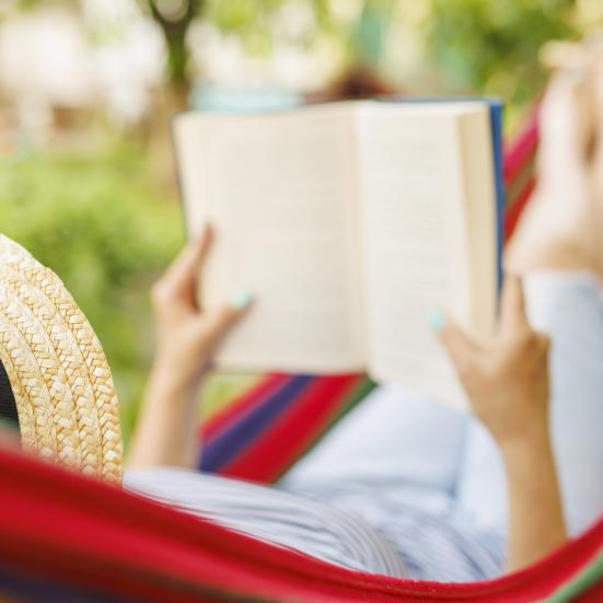 Billede fra Colourbox af kvinde med bog liggende i hængekøje